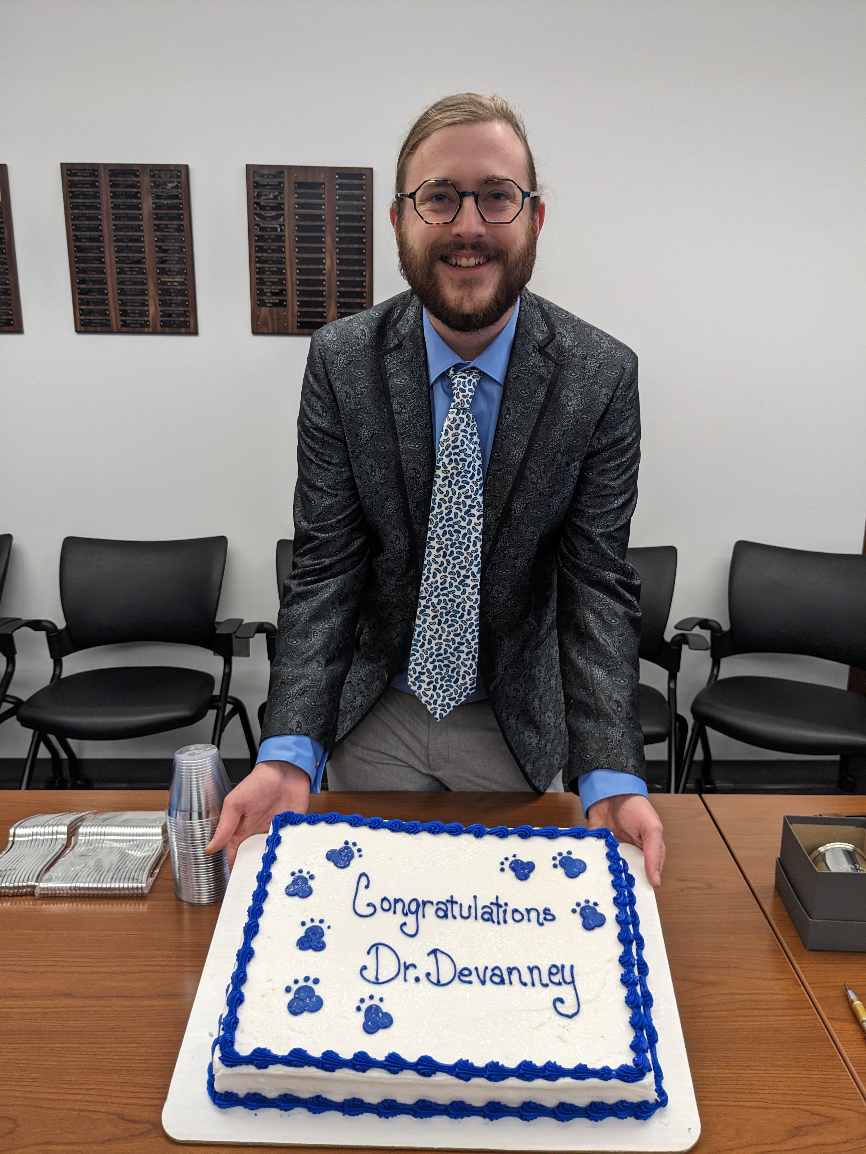 Picture of Dr Devanney holding a cake that says, "Congratulations Dr. Devanney".
