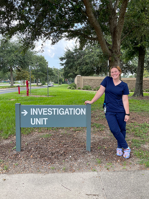 Female intern standing outside by an Investigation Unit sign