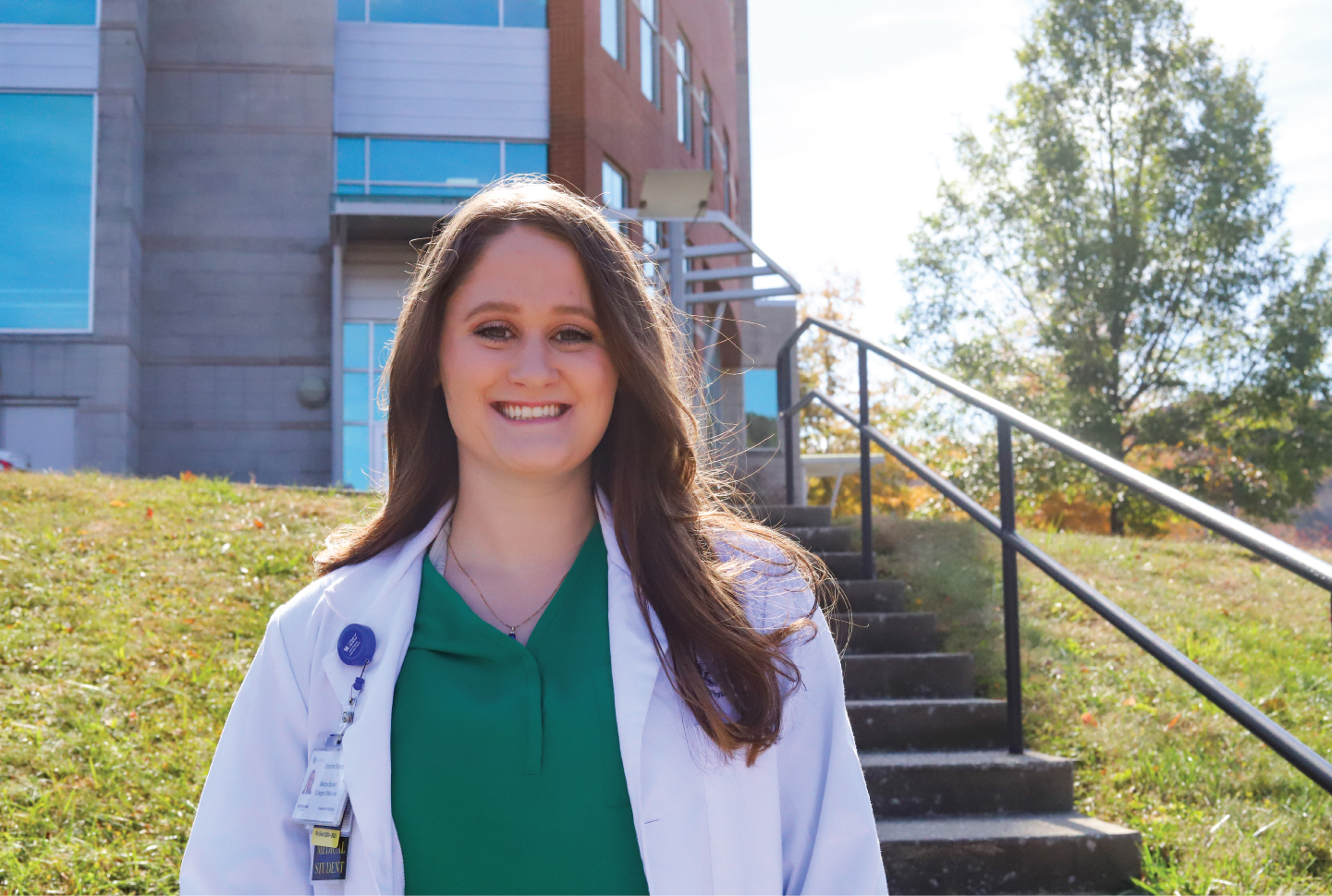 student in a white coat stands in front of Morehead campus