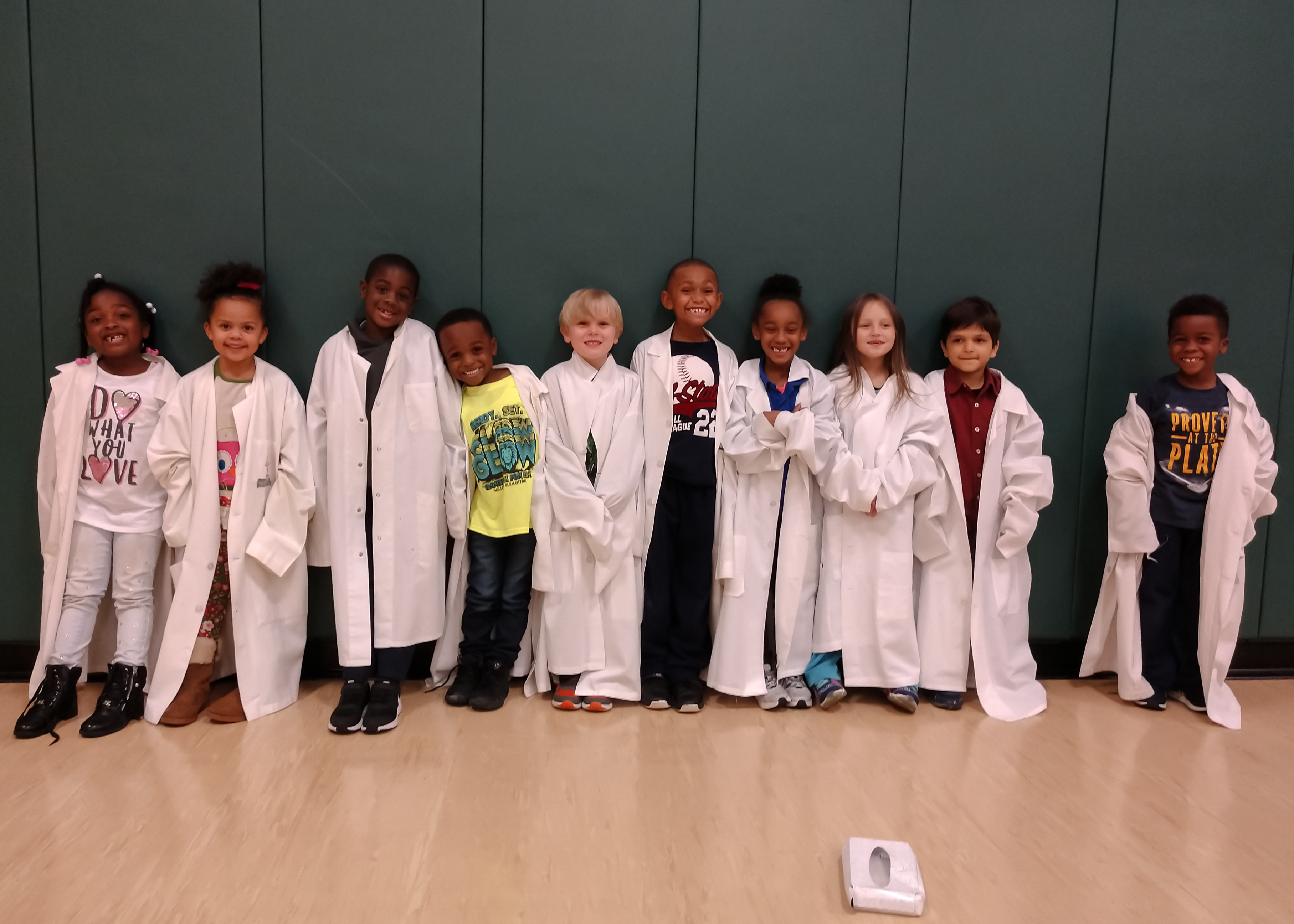 Children in lab coats at event.