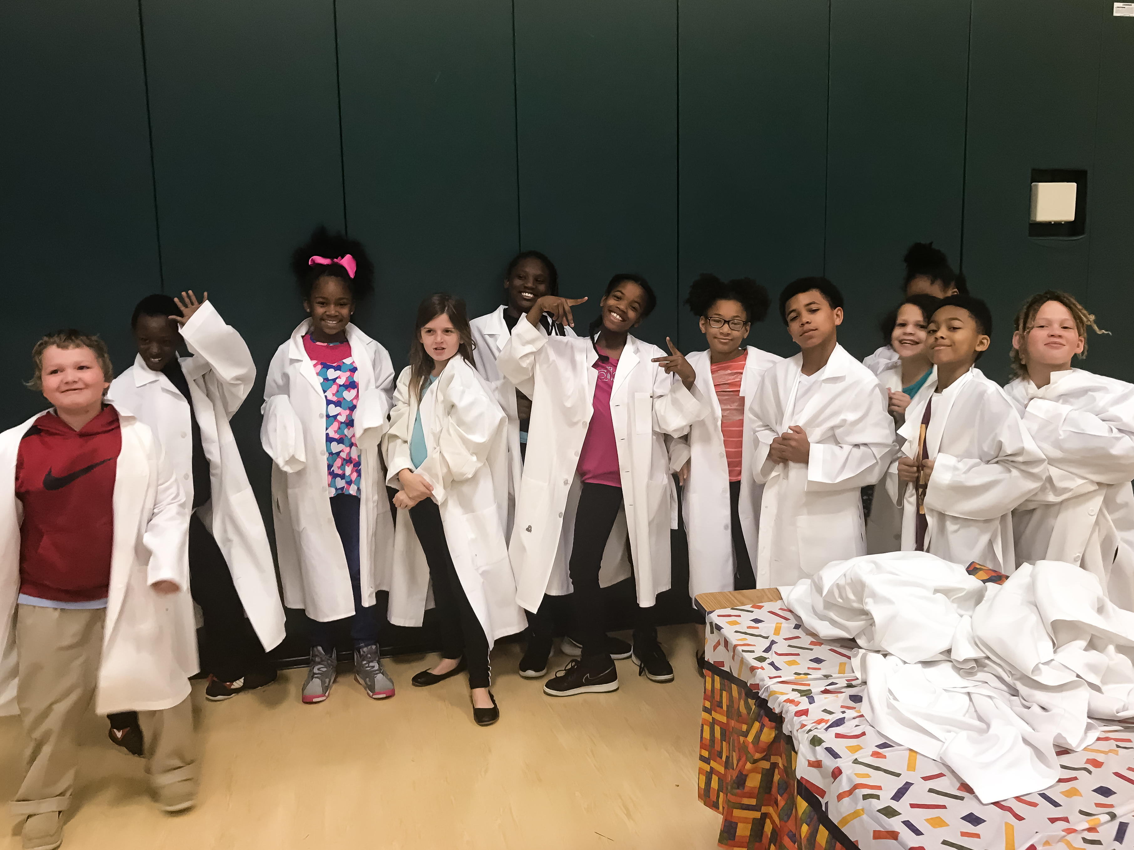 Children in lab coats at event.