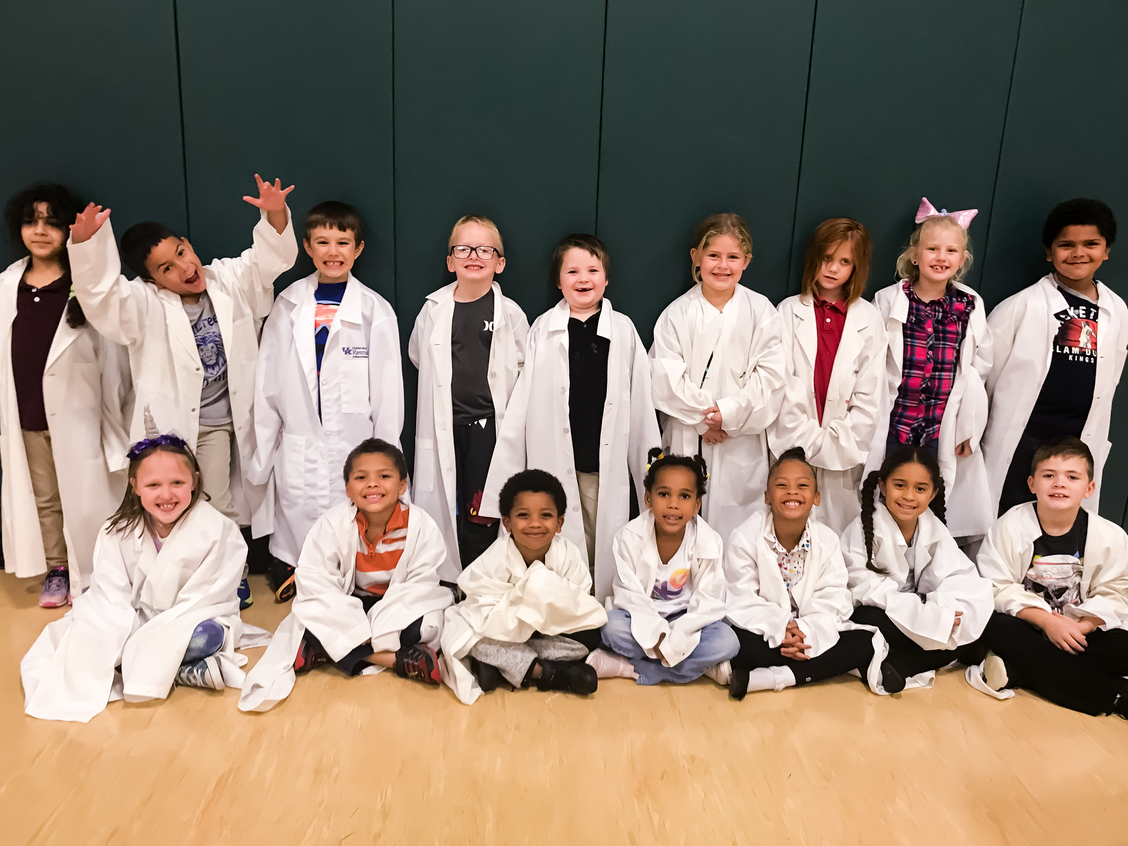 Children in lab coats at event.