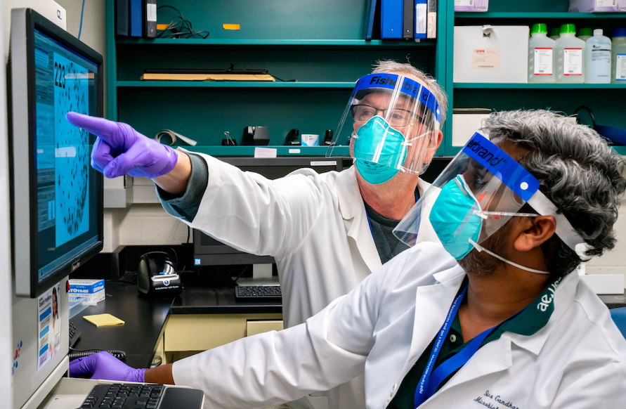 two researchers look at findings on a screen