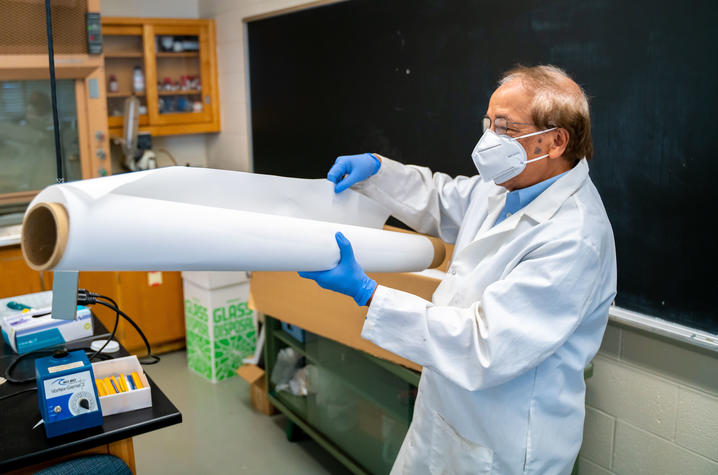 Dibakar Bhattacharyya in the lab with a large sheet of membrane material. Ben Corwin | Research Communications.
