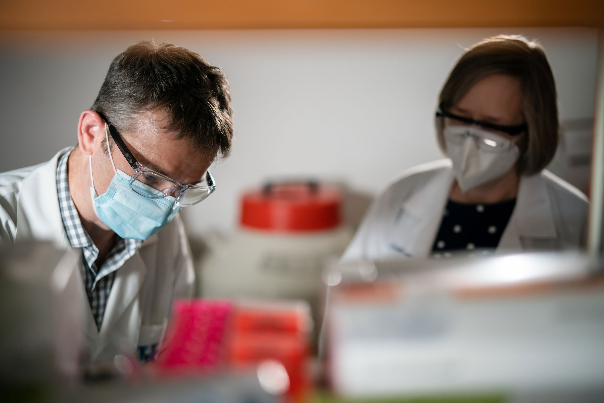 two researchers in a laboratory looking down at something off camera