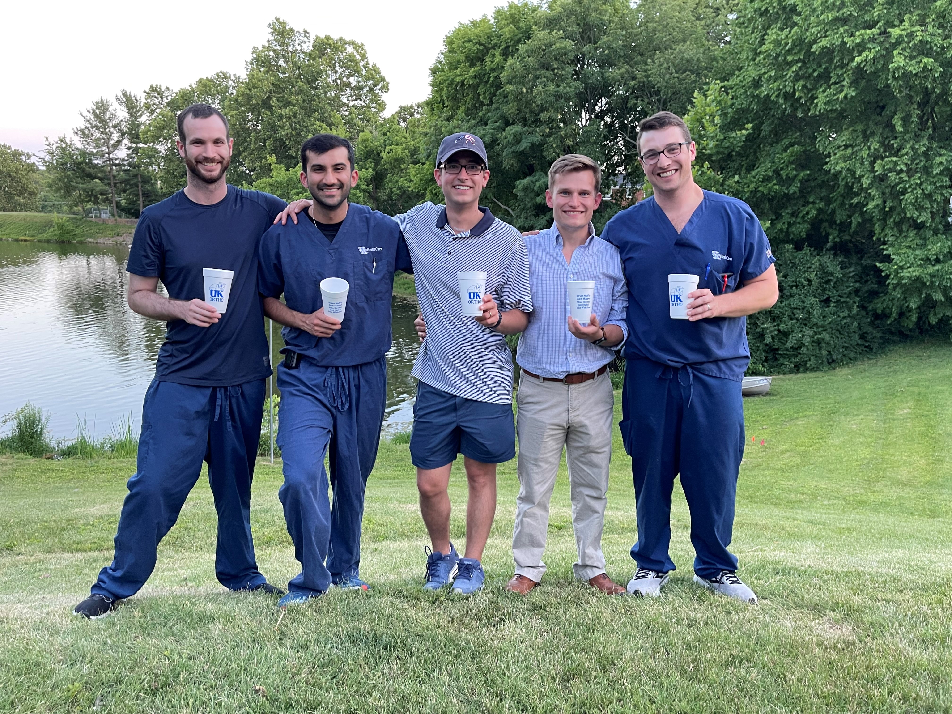 Group picture of ortho residents with pond and trees in background