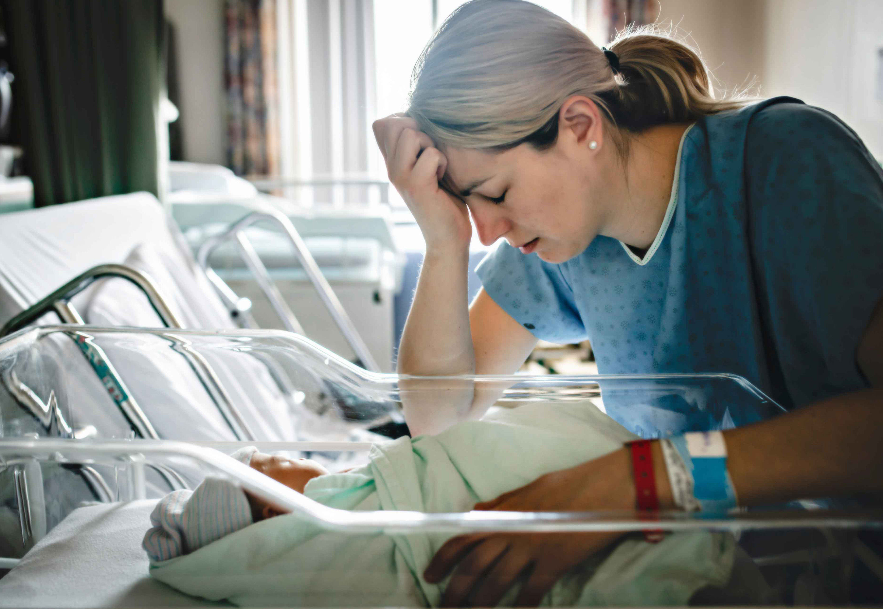 Stressed mother in the hospital, sitting with her baby.