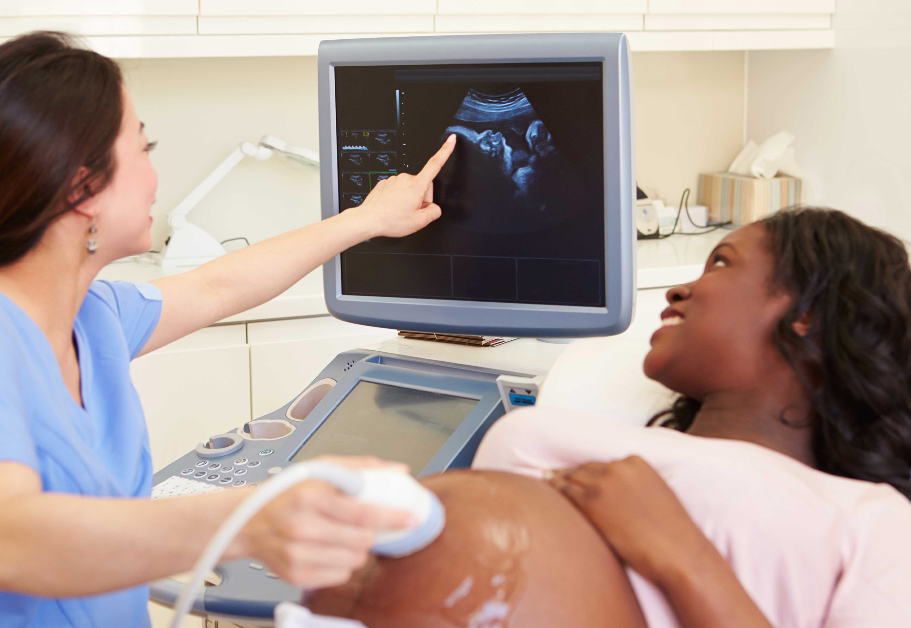Black mother looking at her ultrasound with her female doctor.
