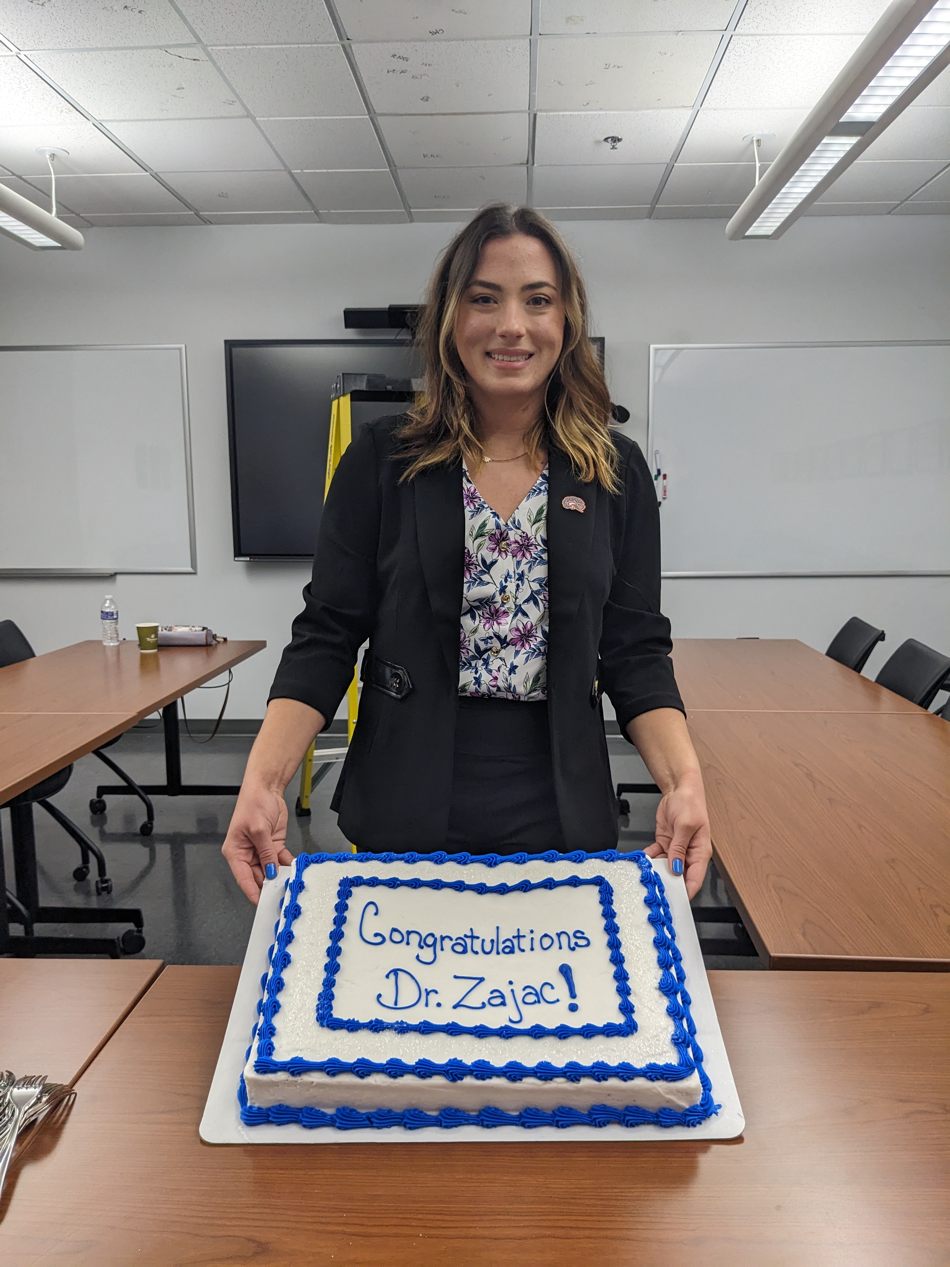 Diana Zajac holding a cake that says "Congratulations Dr Zajac!"