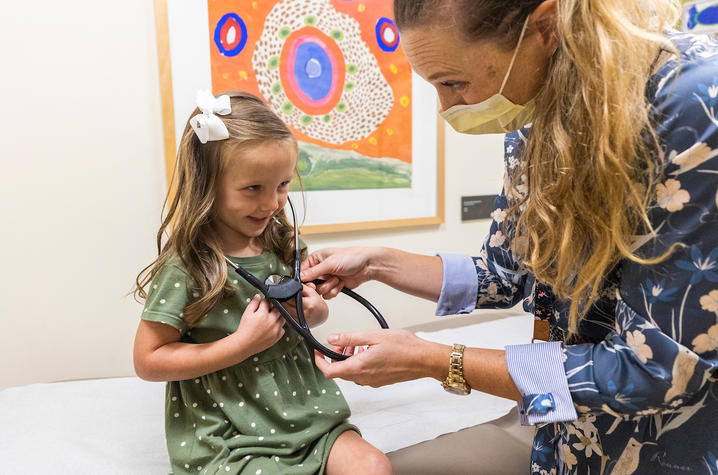 Female doctor letting a little girl listen to her own heart with a stethoscope