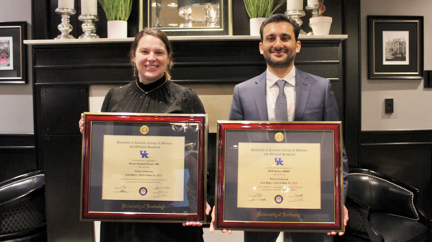 Kristin Hoover and Inu Fawa standing together with their framed degrees.