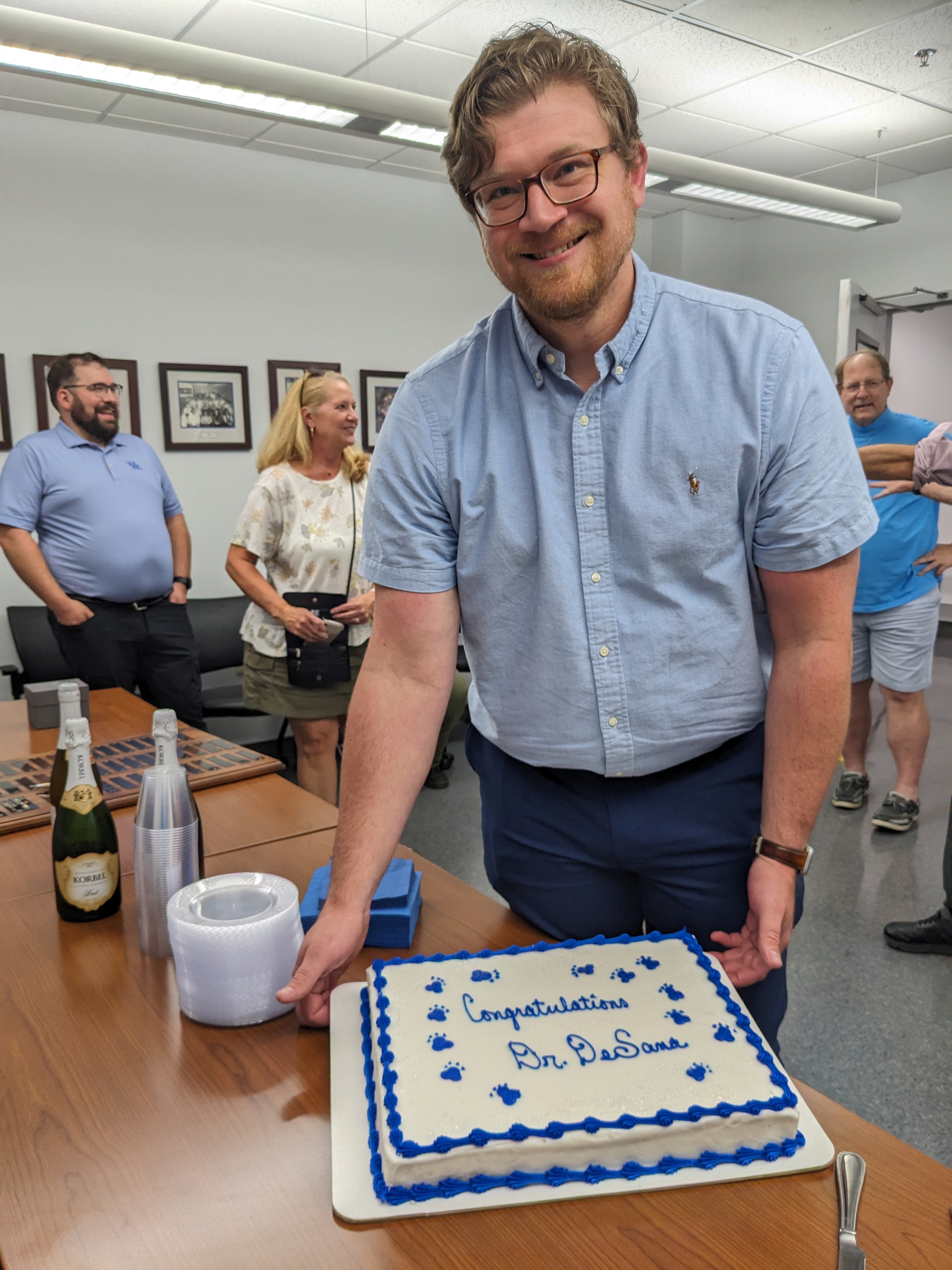 Anthony DeSana holding a cake that says "Congratulations Dr. DeSana!"