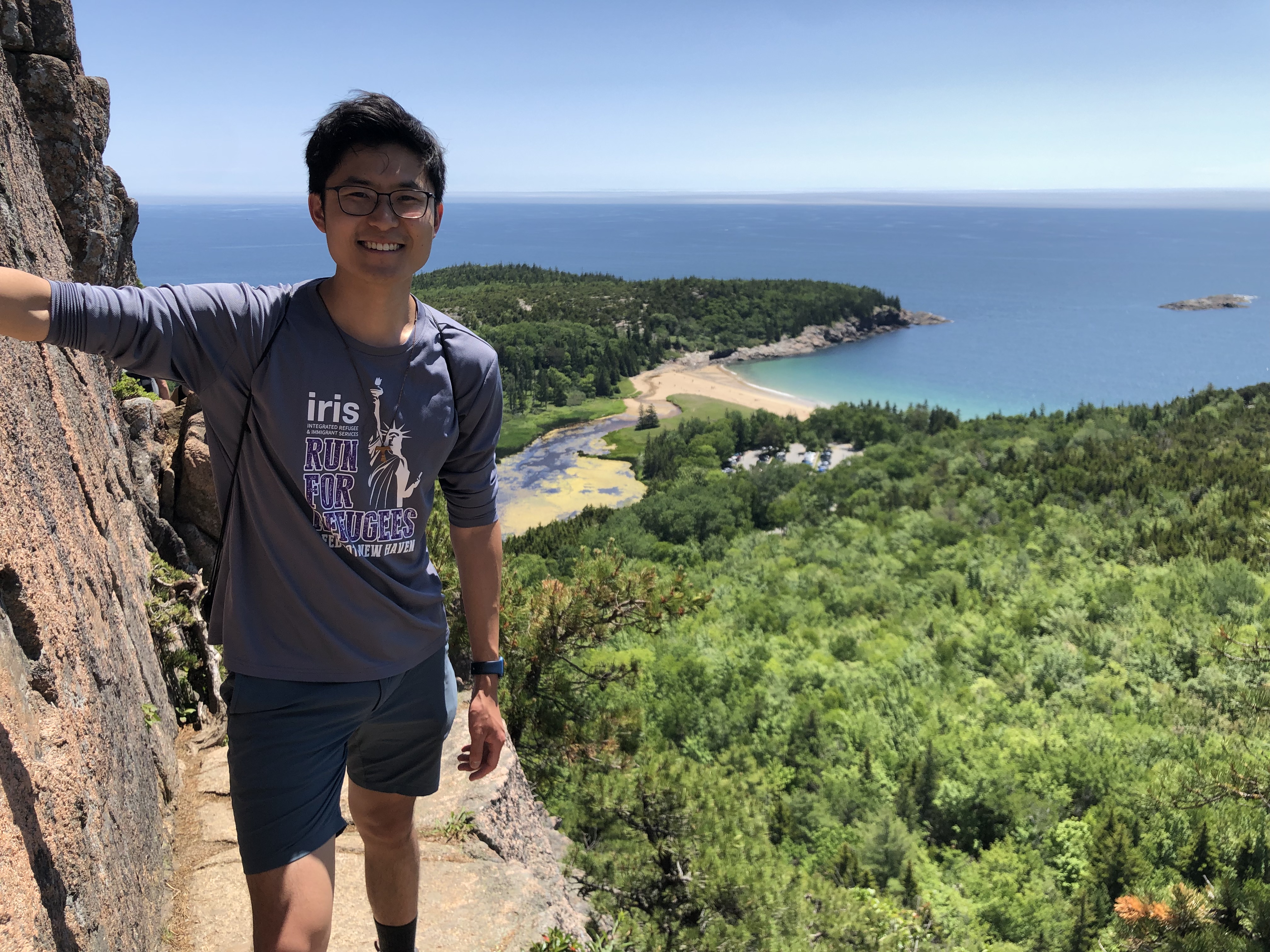 Kevin standing on the edge of a cliff overlooking the ocean and forest. 