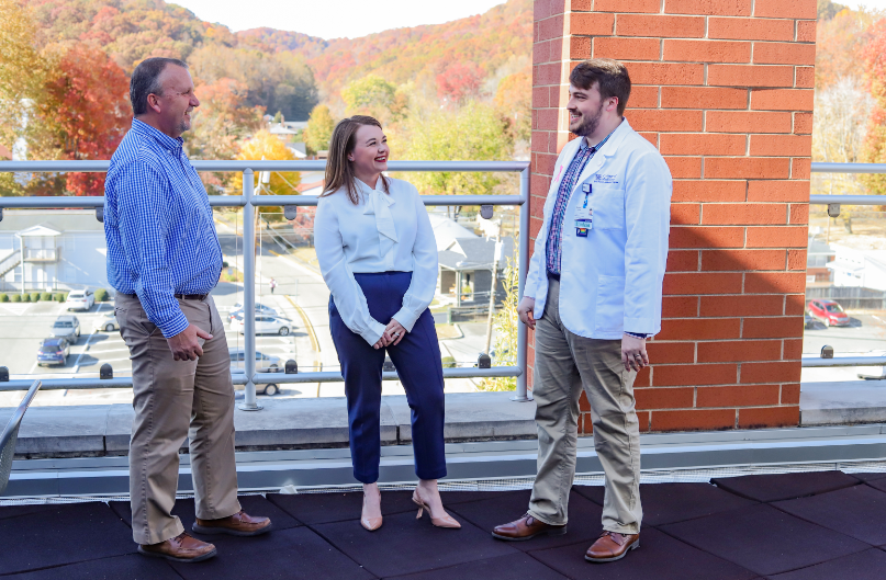 student affairs team member bodie stevens stands and talks to two medical students