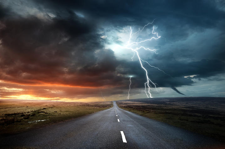 Image of road with thunderstorms and a tornado above