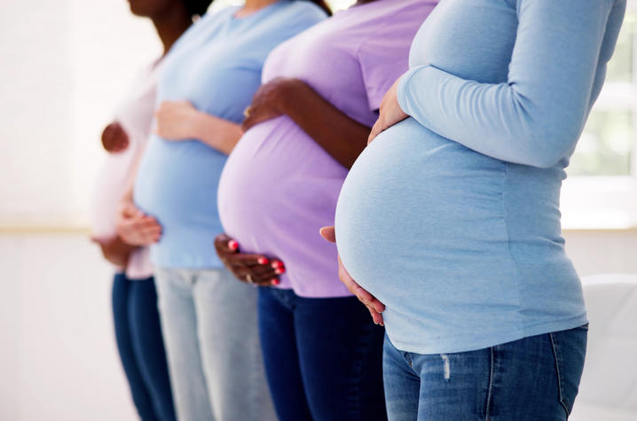 A picture of four pregnant women holding their stomachs