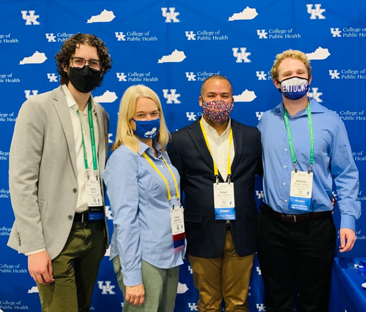 Group of UK faculty and students standing in front of blue backdrop