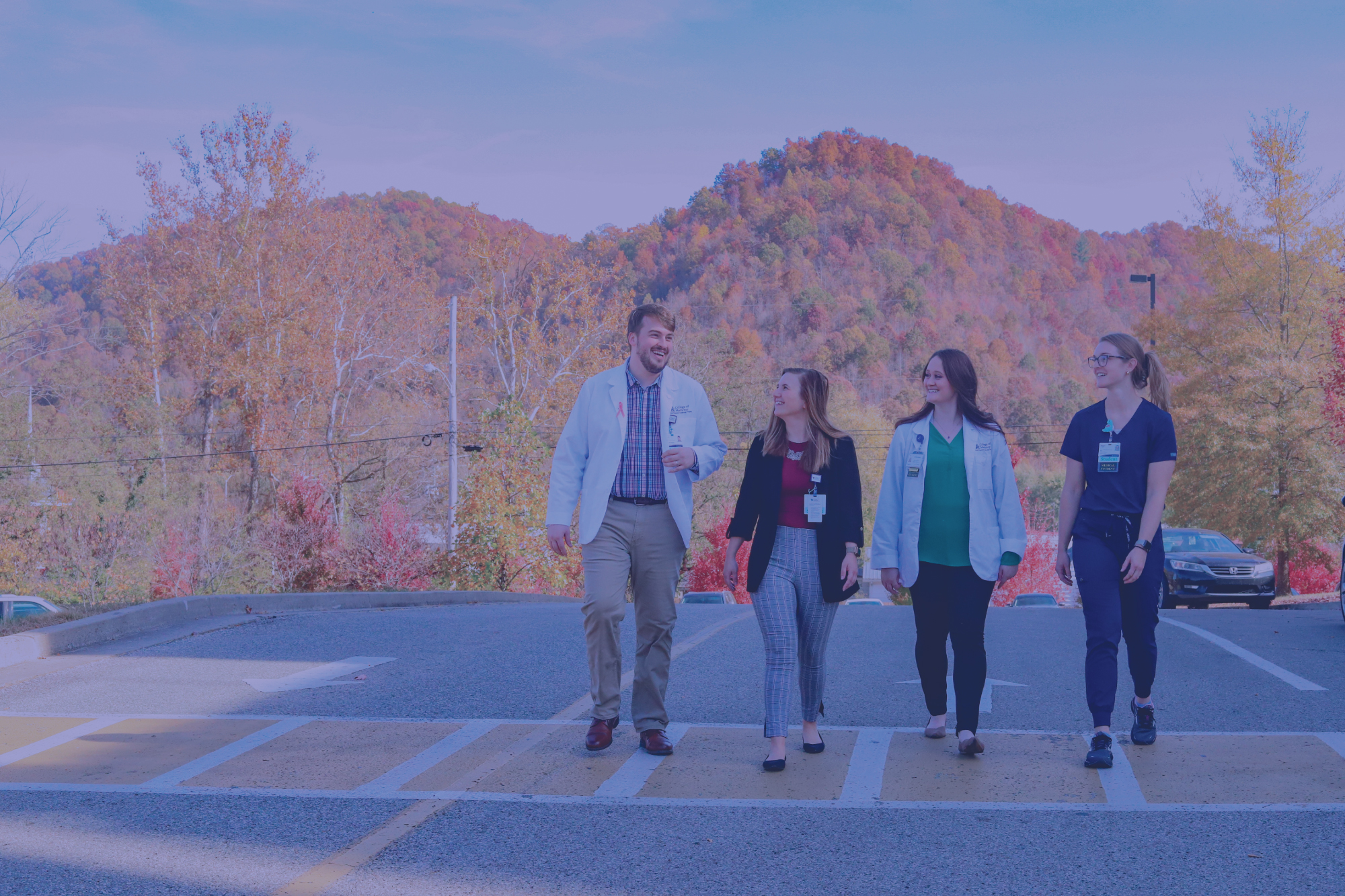 four students walking down the street with mountains behind them