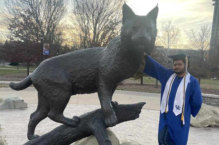Devin Thompson standing with the wildcat statue.