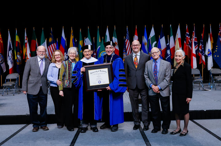 John Rosenberg and UK President Eli Capilouto hold Rosenberg's honorary degree, with Rosenberg's family and friends.