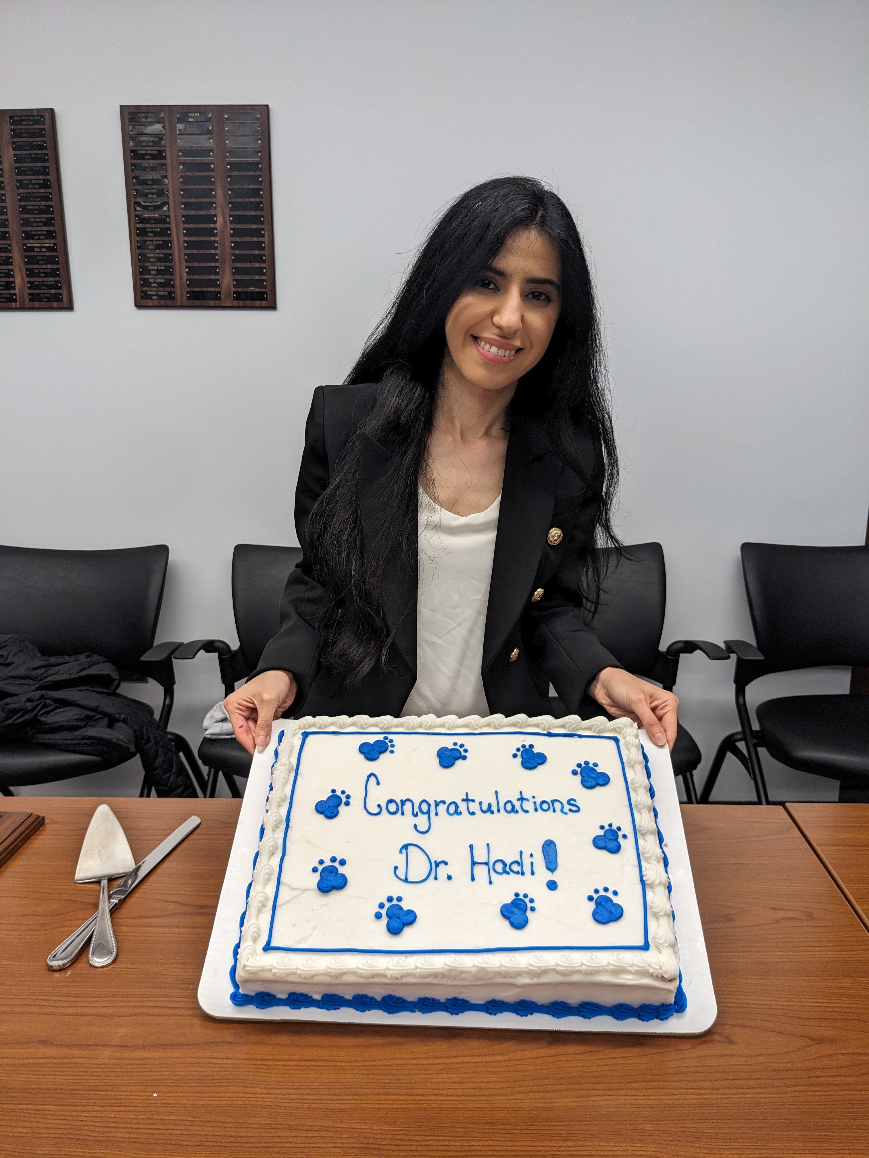 Shadan Hadi holding a cake that says "Congratulations Dr. Hadi!"