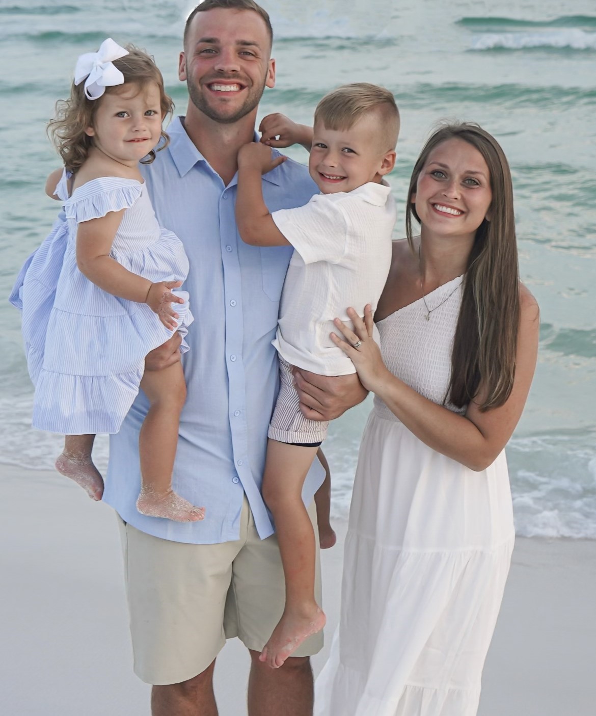 Ryan Harpole standing with his family smiling at the beach with the sea behind them. 