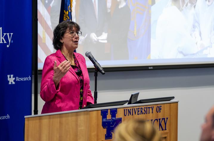 Monica Bertagnolli at a podium, addressing a University of Kentucky audience. 