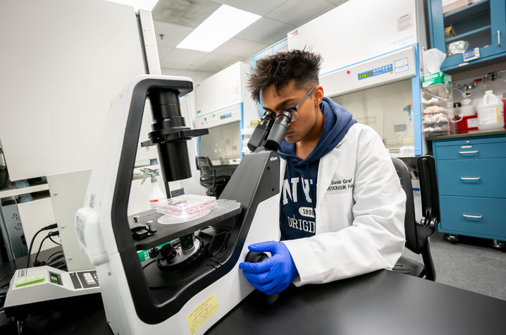 Preet Patel working at a microscope in the laboratory.