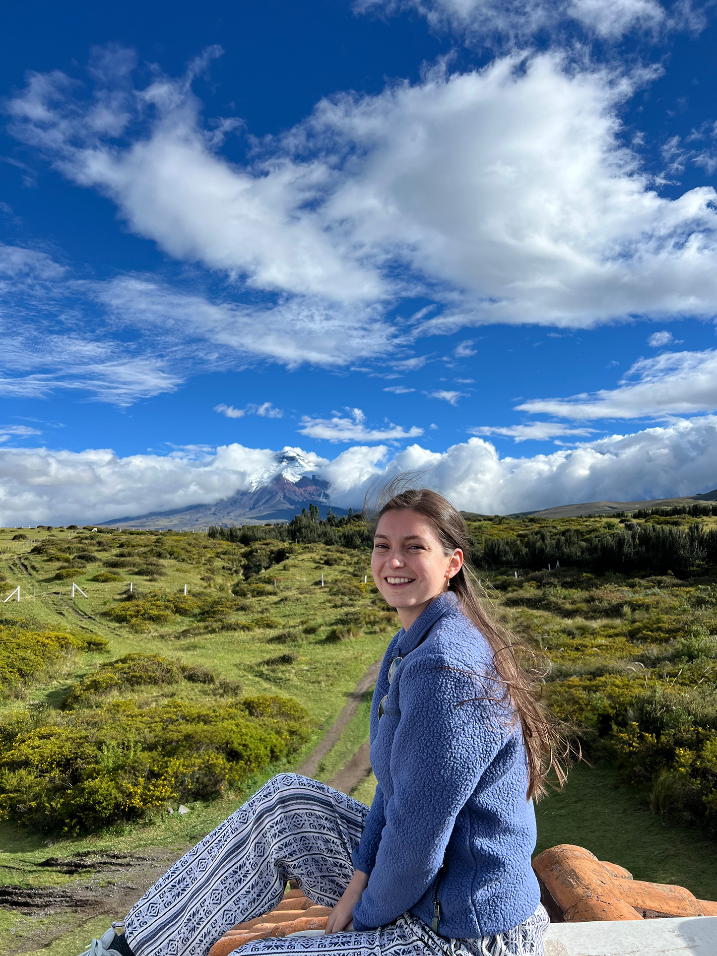 Emily Ranseen sitting on top of a hill in front of a bright blue sky