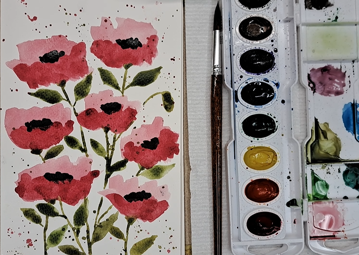 A watercolor painting of poppies, side-by-side with a palette of paints.