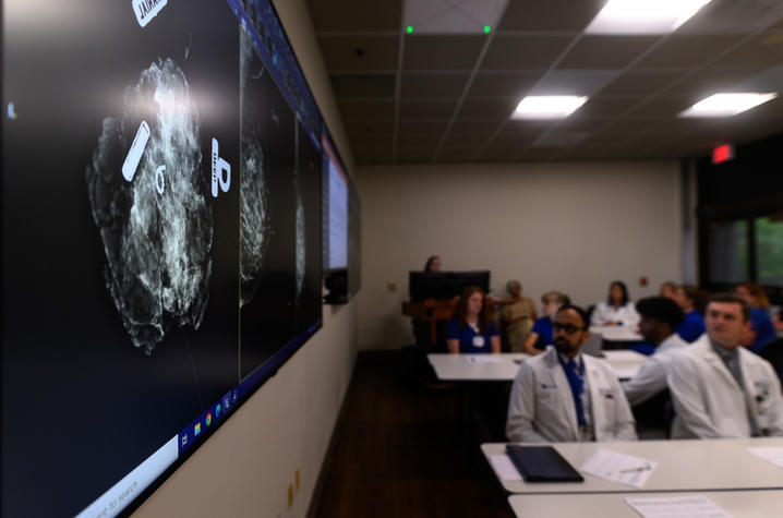 A room of medical professionals looking at boards of cancer screenings.