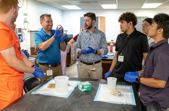 A faculty mentor signing to several student about the experiment in front of them.