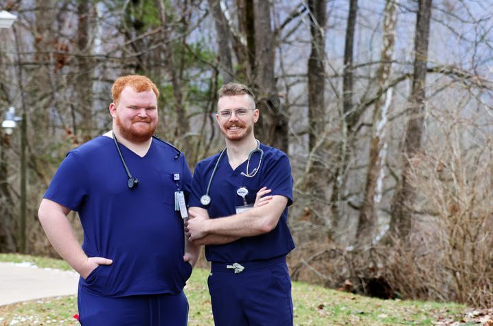 Alex Willett, left, and Bradley Firchow standing in front of a tree line