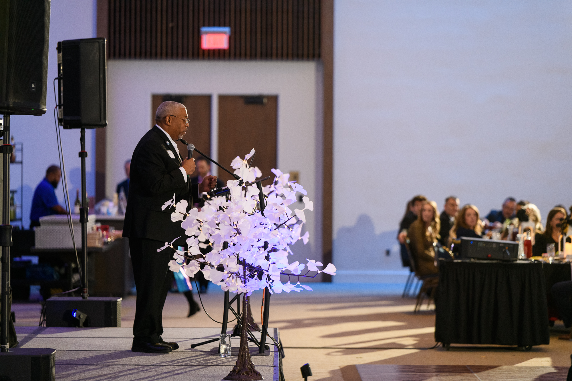 Dr. Conwell dresses a listening audience, standing on a stage with a microphone