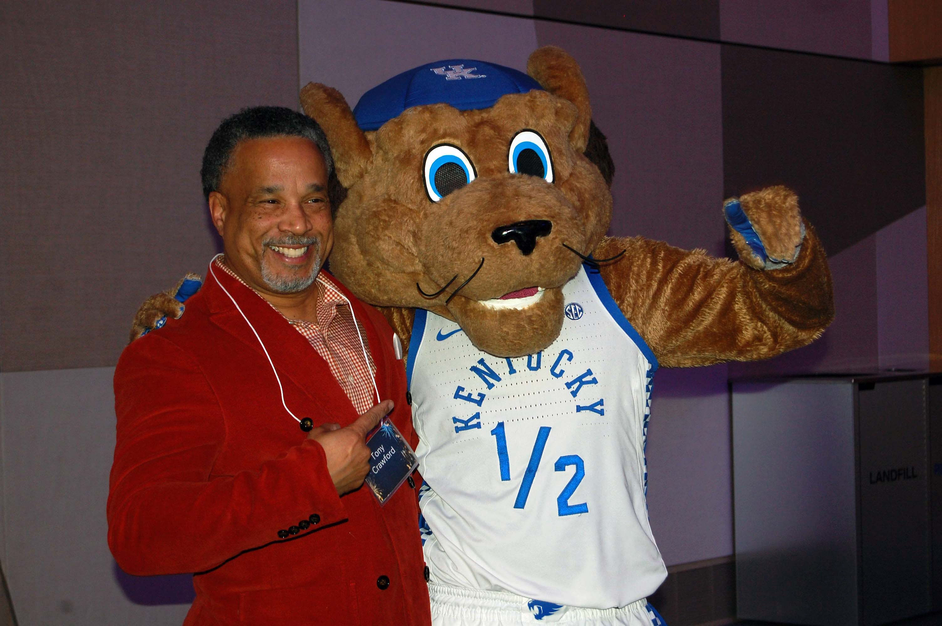 A man in red poses with Scratch the wildcat mascot