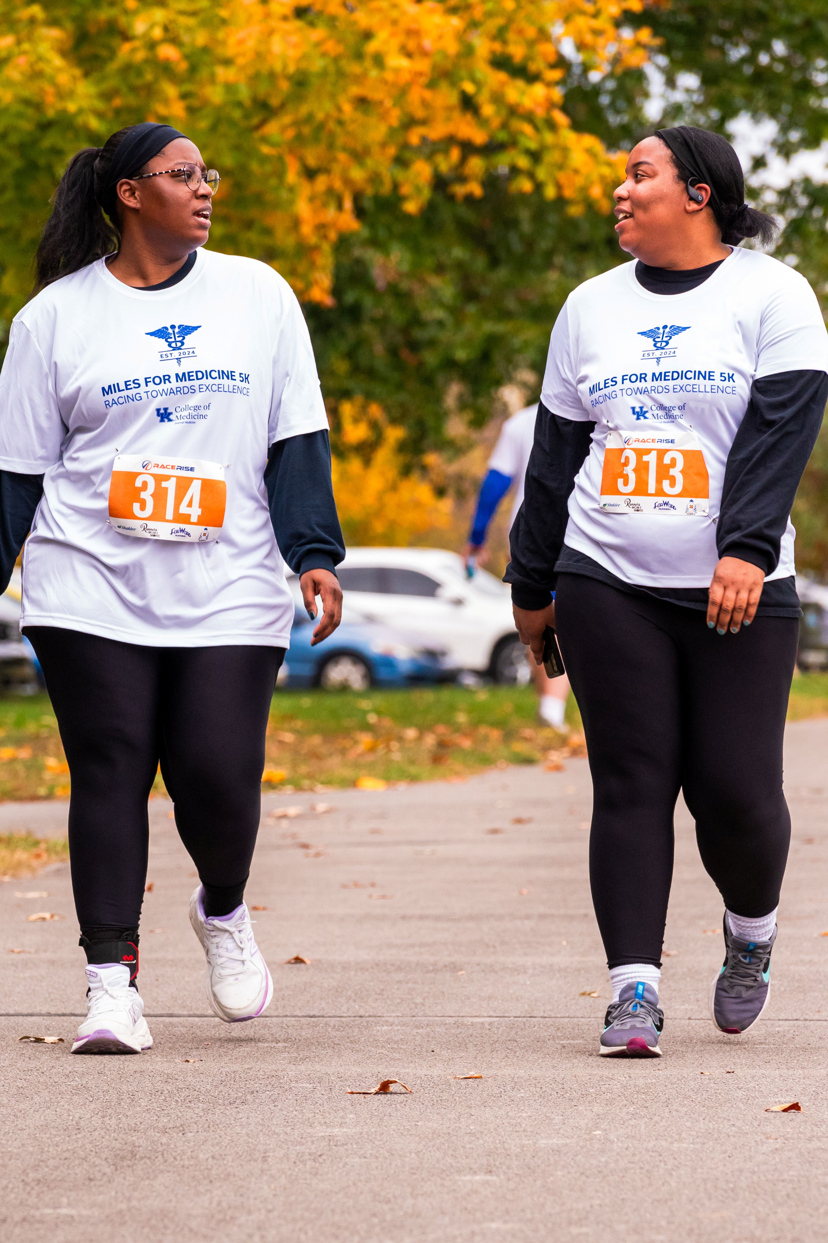 Two women look at each other as they cross the finish line, walking.