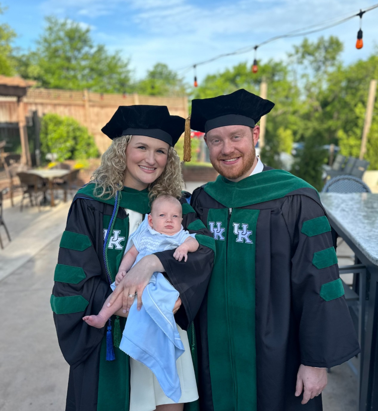 Abigail and Jason Hurt pose in graduation regalia with newborn son, Griffin