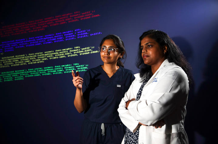 Dhanya Gorty, MD and Rani Priyanka Vasireddy, MD observing a virtual wall of code.