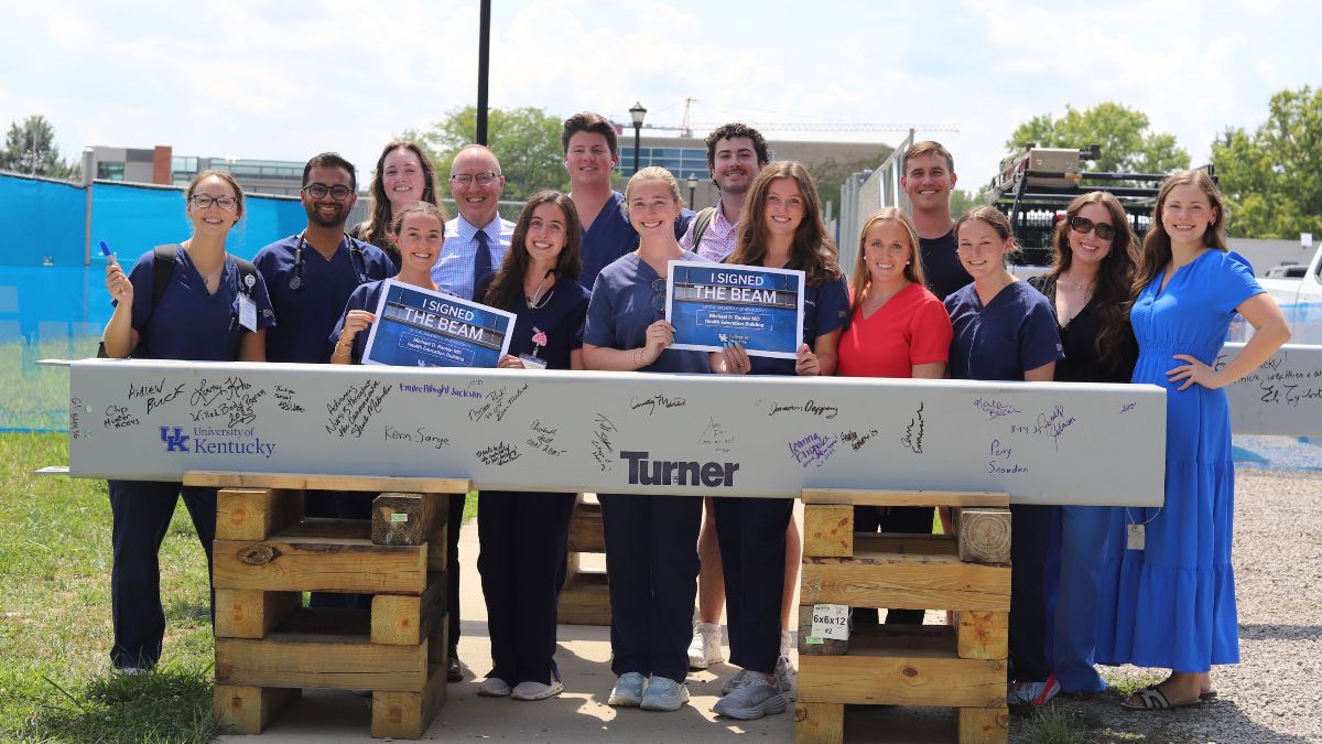 Several students pose with signed ceremonial beam. 