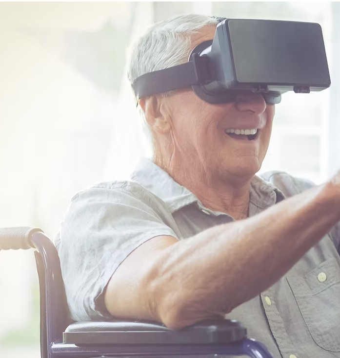 Elder man in wheelchair smiles while wearing a VR Headseat