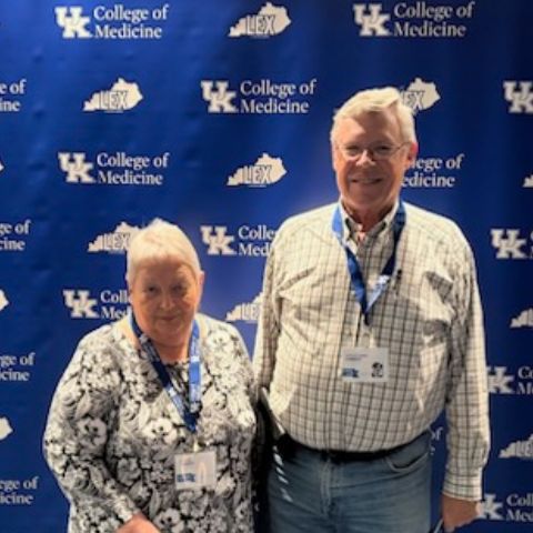 Dr. Chrest and his wife pose in front of UK background during 50th alumni reunion event 