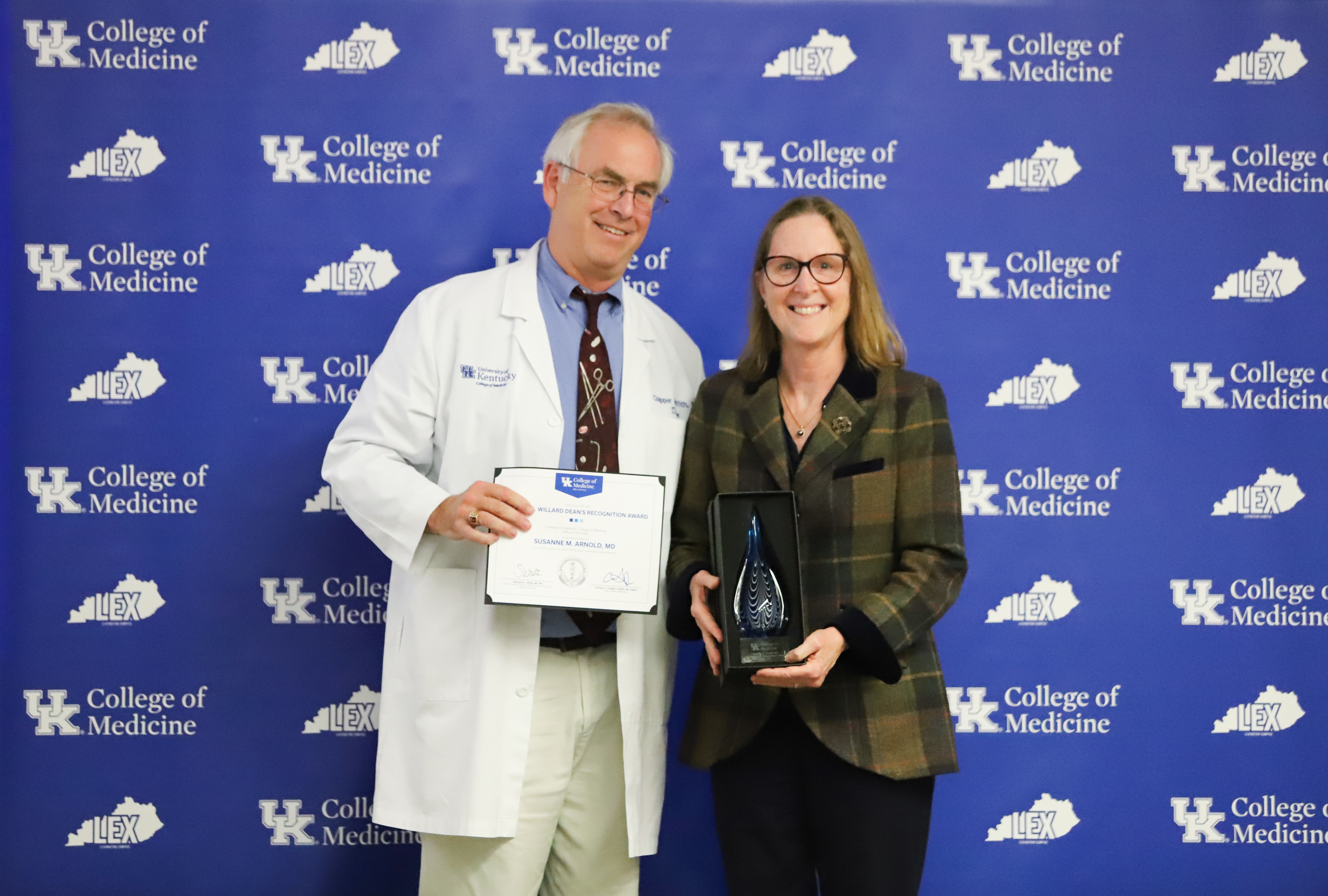 Dr. Griffith and Dr. Arnold pose for a photo in front of a blue background