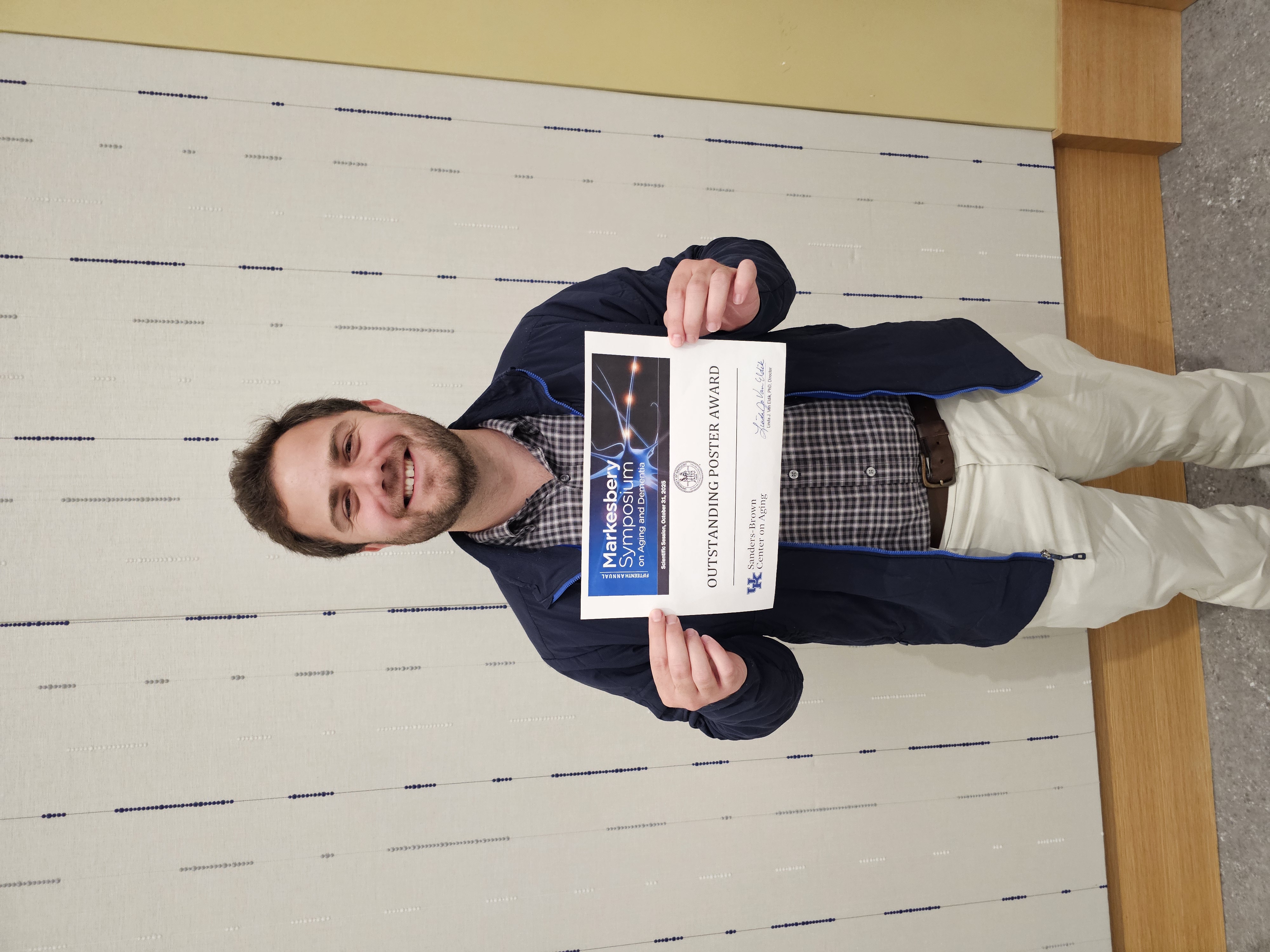 A photograph of a DPNS Graduate Student with his award for his outstanding poster