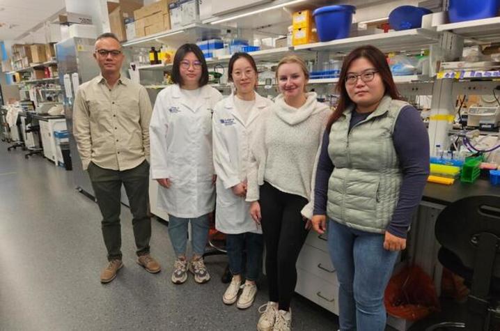 Fong with members of his lab, standing in front of their lab station. Conveying a unified presence.