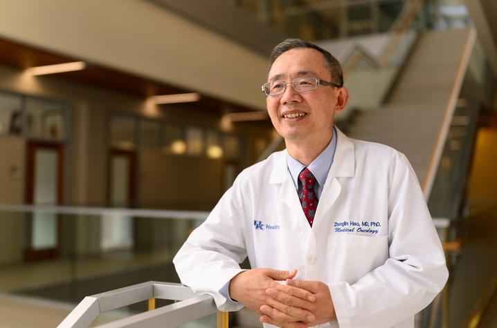 Zhonglin Hao, dressed in white coat, and leaning against the bottom of the stairway in the UK Pharmacy building.