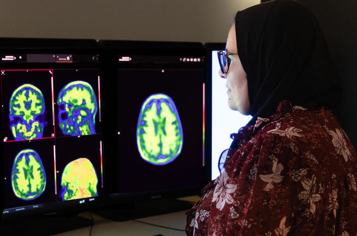 Riham El Khouli, MD, sits in a dark computer lab, examining brain scans that highlight in a range of vivid colors.