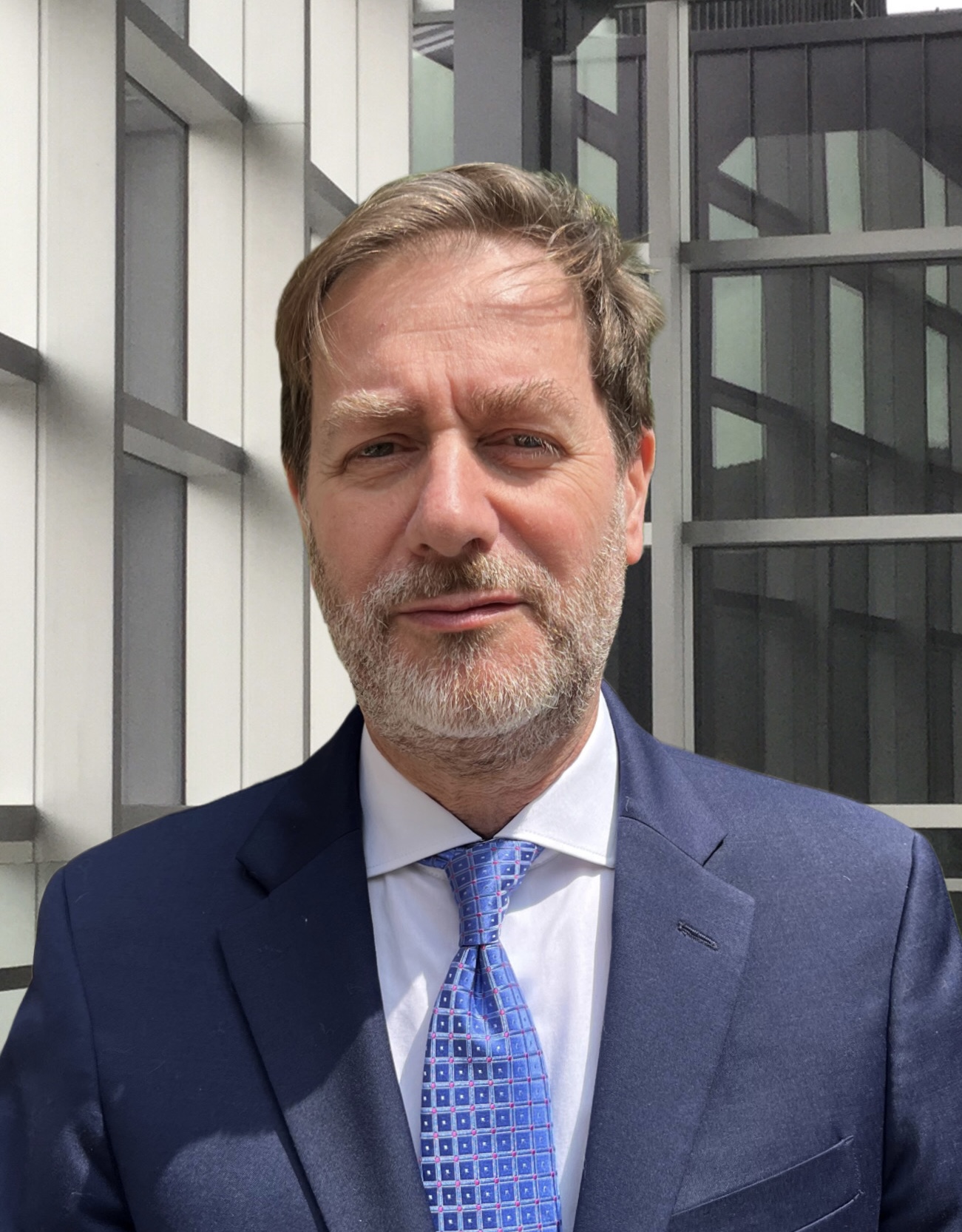 Dr. Pierluigi Porcu stands in a blue suit and blue tie with a white undershirt. He smiles in his headshot.