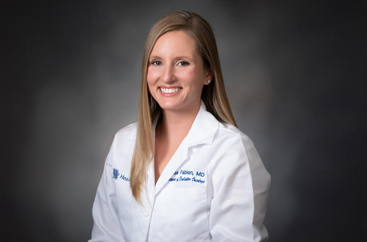 Denise Fabian - A blonde woman wearing her white coat - smiling, conveying positivity and professionalism.