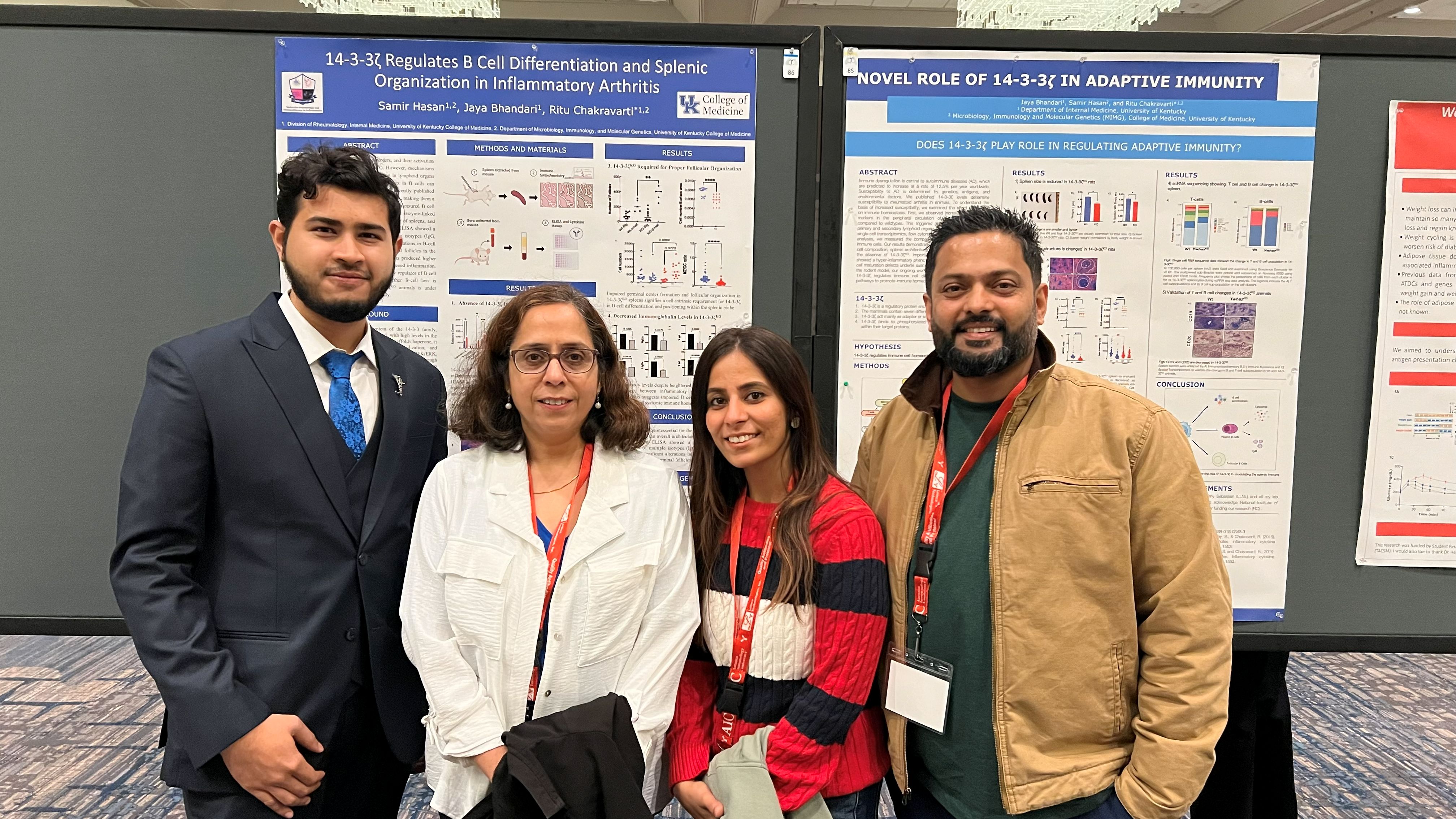 A group pose for a photo together, standing in front of a board containing research posters
