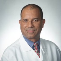 A headshot of Hender Rojas in a white coat